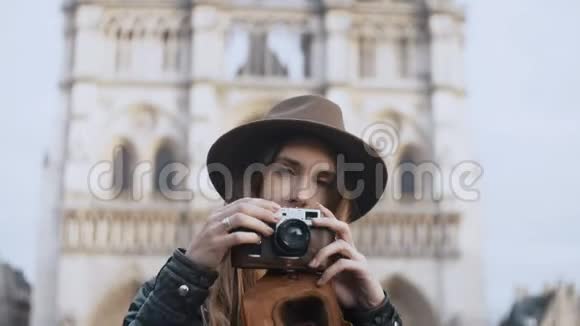 年轻美丽的女人站在法国巴黎圣母院附近在复古电影相机上拍照视频的预览图