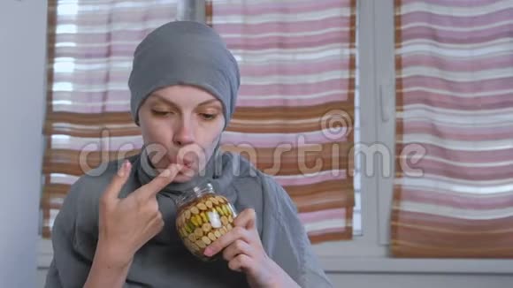 戴头巾的穆斯林妇女用手指蘸蜂蜜把坚果放进罐子里从手指上吃蜂蜜视频的预览图