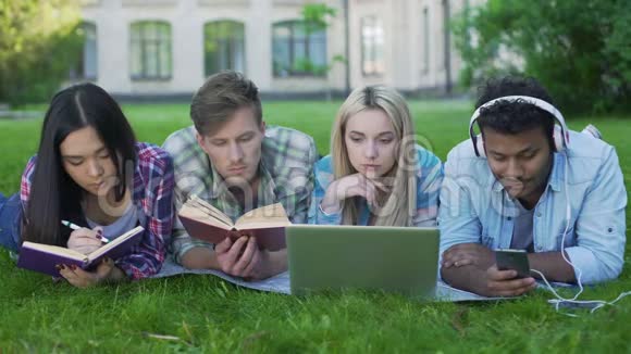 混合种族学生躺在草地上准备考试大学教育视频的预览图