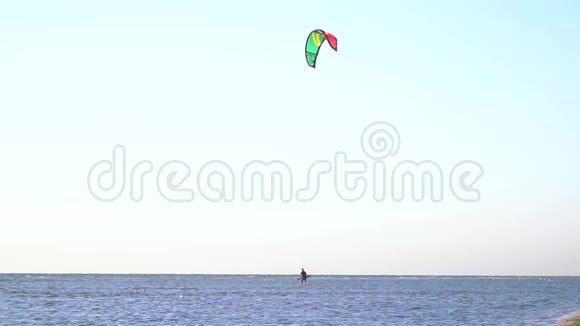 慢动作射击男子在浅水中行走控制着天空中的训练风筝视频的预览图