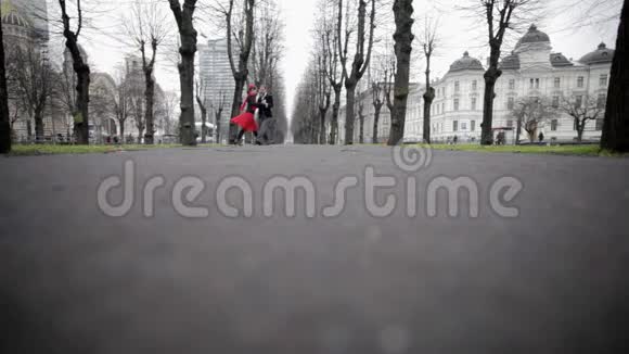 穿着天鹅绒西装的男人和穿着红色裙子的女人在冬天的公园里跳舞视频的预览图