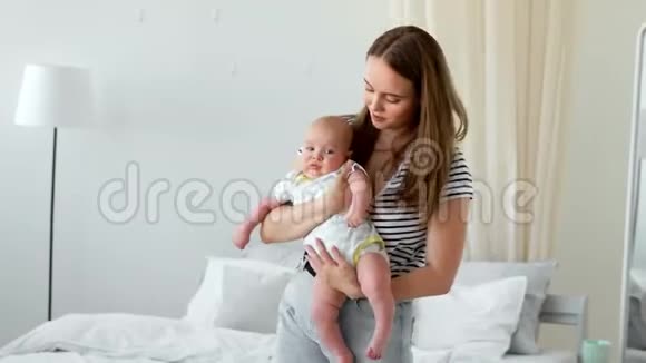 白色公寓中现代年轻家庭的概念妈妈让婴儿上床睡觉给他唱摇篮曲视频的预览图