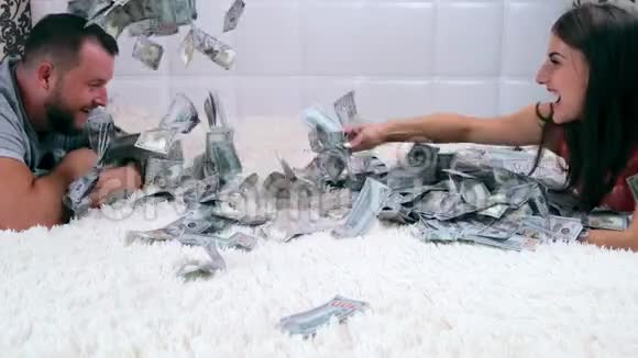 一个男人和一个女人坐在一张白色的床上分享金钱享受匆忙的乐趣并考虑他们从上面看很多视频的预览图