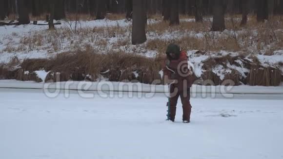 渔夫在冰上钻洞在冬天钓鱼视频的预览图