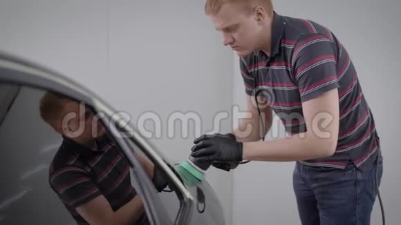 一个在车库里用磨光机处理黑车的人视频的预览图