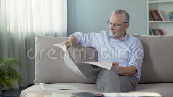 年长男性坐在沙发上看报纸早晨仪式按视频的预览图