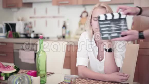 拍手板在厨房的桌子旁坐着一个可爱的金发女人面前拍手视频的预览图