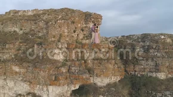 新婚夫妇站在悬崖边新郎温柔地拥抱新娘视频的预览图