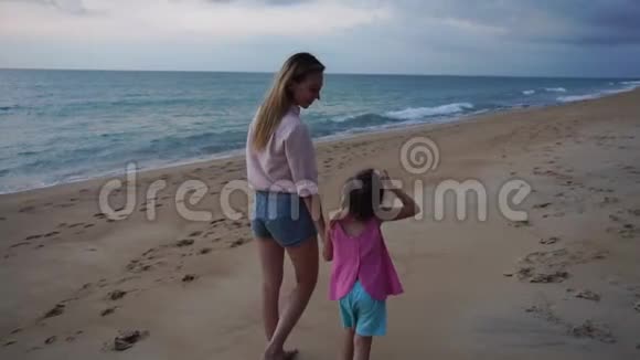 动作缓慢的母亲和小女儿晚上在海边散步视频的预览图