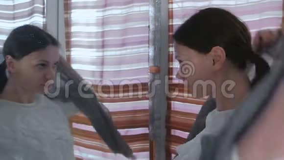 年轻漂亮的女人站在家里的镜子前头上戴着灰色的头巾视频的预览图