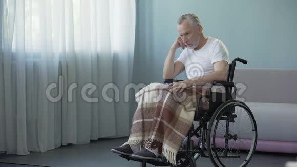 坐在轮椅上在养老院等家人的男性养老金领取者视频的预览图