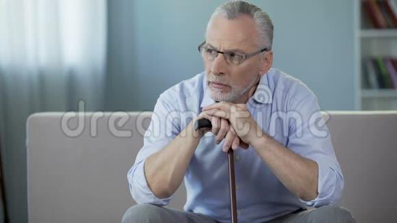 50多岁的病人坐在沙发上双手放在手杖上抑郁症视频的预览图