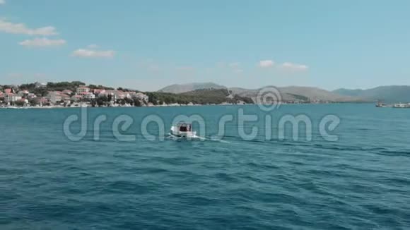 鸟瞰一个小的旧快艇与一个人移动在蓝色水晶清澈的海洋视频的预览图