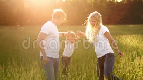 幸福的家庭爸爸妈妈和儿子在情感上散步在新鲜空气中的绿色田野里奔跑和享受生活蓝色视频的预览图