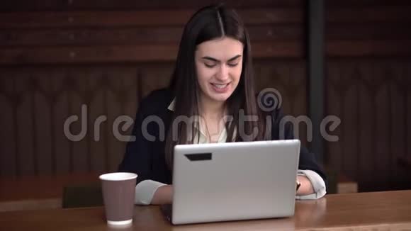 在咖啡馆打手提电脑和喝咖啡的浅黑色女孩视频的预览图