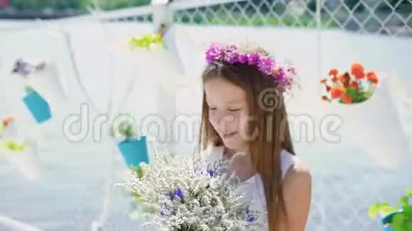 快乐的小女孩带着一束花在阳光明媚的日子里四处张望4K视频的预览图