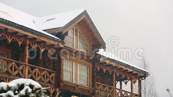 在大雪纷飞期间可以近距离观看带有夹层的山村小屋带有俄罗斯风格雕刻的木制立面视频的预览图