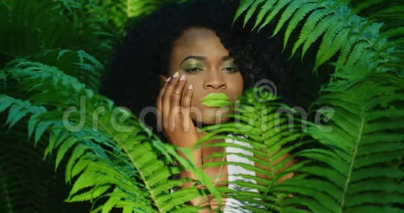 这位美丽的美国黑人妇女的近景她涂着绿色的口红和眼影抚摸着自己的脸颊视频的预览图