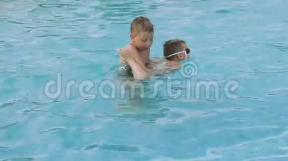 哥哥教一个弟弟戴着游泳眼镜在游泳池里游泳视频的预览图