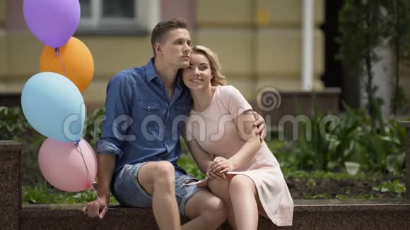 恋爱中的人坐在长凳上男人拿着气球无忧无虑的浪漫心情视频的预览图