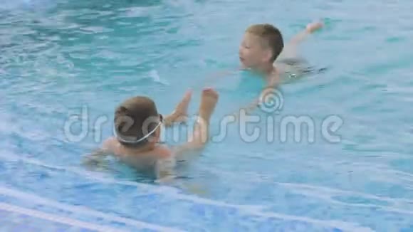 戴着游泳眼镜的男孩和弟弟在游泳池里游泳视频的预览图