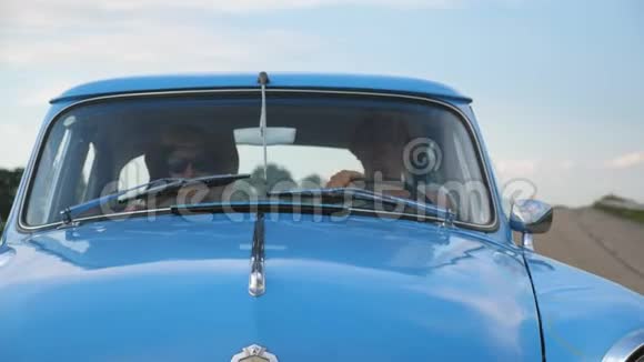 年轻夫妇戴着帽子在夏季旅行时坐着老式汽车幸福的男人和女人坐在老人的前排视频的预览图