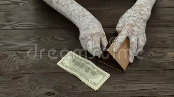 女人手戴着白色花边手套数着一个黑色皮包里的美美分硬币视频的预览图