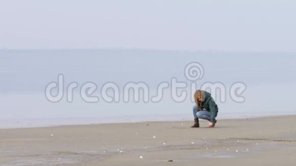 美丽的女孩在海滩上的沙滩上画画写字视频的预览图