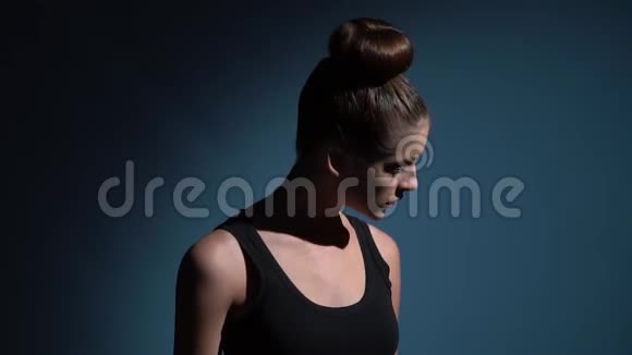 一个穿着黑色T恤的苗条女孩正在蓝色背景上跳舞视频的预览图