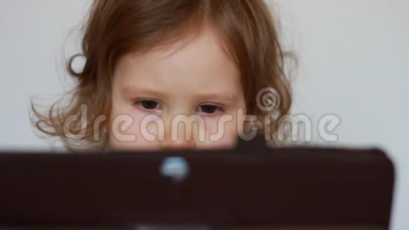 特写孩子看平板电脑屏幕播放下载的应用程序一个小可爱的女孩坐在桌子旁视频的预览图