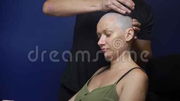 男人用蓝色背景的电动剃须刀剃光头女人化疗效应的概念视频的预览图