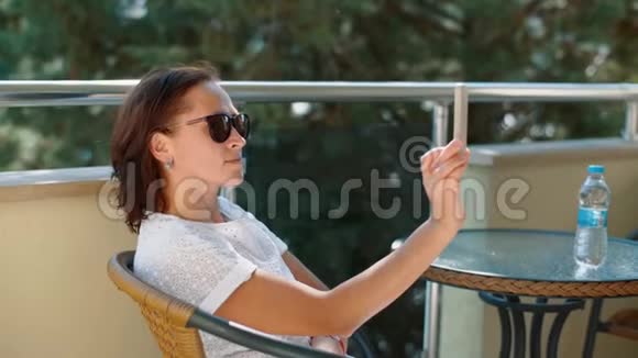 一个穿白色连衣裙的女人在阳台上自拍视频的预览图