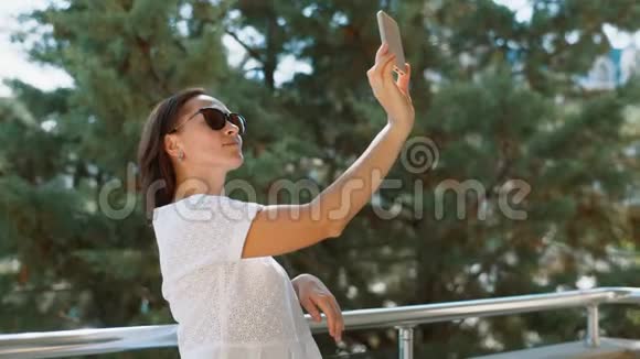 一个穿白色连衣裙的女人在阳台上自拍视频的预览图