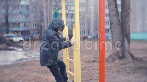 一个男孩爬在一座城市房子的院子里的猴栏上游戏和在游乐场散步视频的预览图