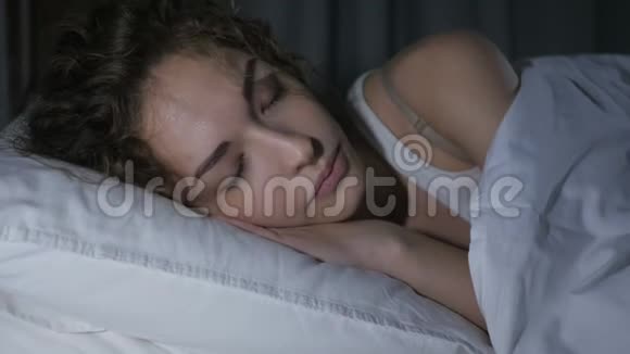 夜晚睡在黑暗卧室的美丽年轻女性视频的预览图