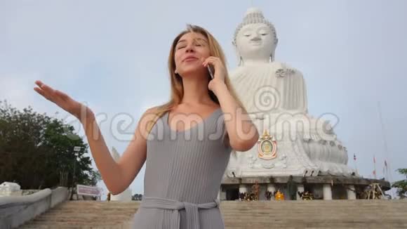 泰国佛像附近的一位慢动作旅游女士在智能手机上聊天视频的预览图