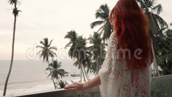 年轻女子站在阳台上俯瞰大海视频的预览图