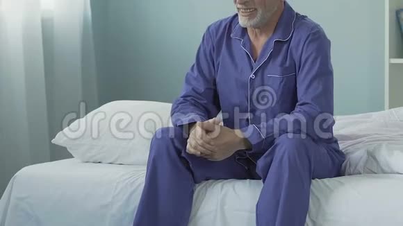 精神饱满的男人早上坐在床上微笑伸展身体快乐的退休视频的预览图