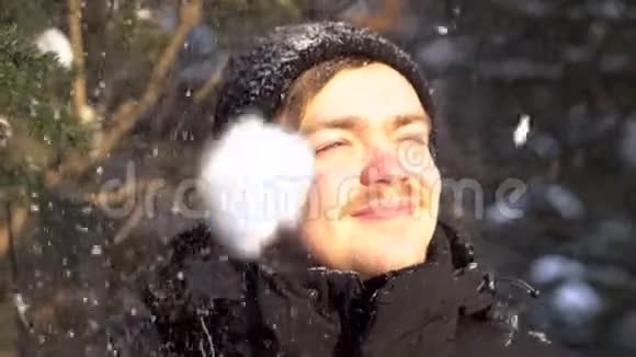 在冬天的森林里留着小胡子小胡子面带笑容的年轻男子欣赏着降雪的从灿烂的阳光中眯起眼睛视频的预览图