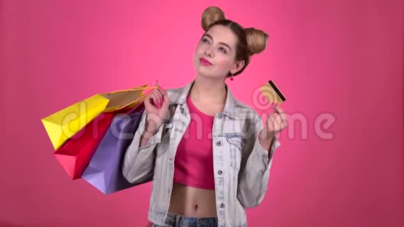 青少年拿着购物袋和一张金信用卡粉色背景视频的预览图