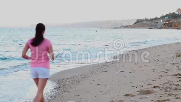 在海边沙滩上慢跑的女孩视频的预览图