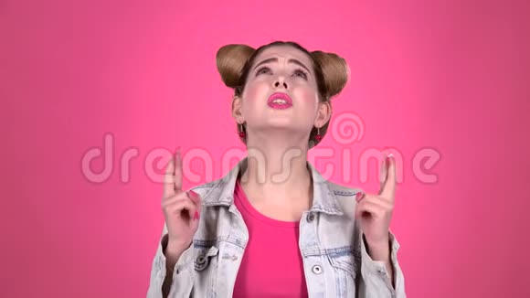 女孩祈祷她的手指粉色背景视频的预览图