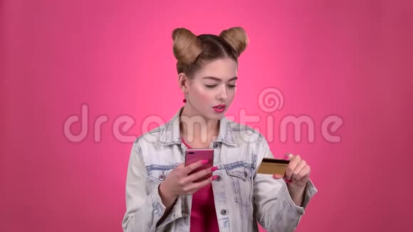 他手里拿着信用卡和电话粉色背景视频的预览图