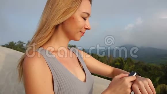 慢动作健身教练女孩在酒店阳台测试智能手表视频的预览图
