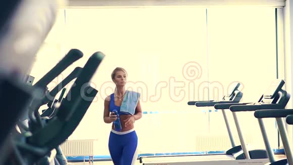 经过艰苦的训练女运动员从蓝色的塑料瓶中喝水视频的预览图