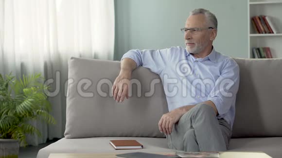 快乐的成熟男人坐在沙发上回忆去年暑假视频的预览图