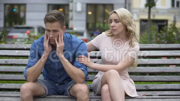 担心的家伙坐在长凳上女朋友让他冷静下来问题支持视频的预览图