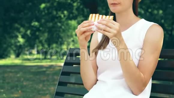 饥饿的女人在公园吃三明治游客在公共公园享用午餐享受夏日阳光视频的预览图