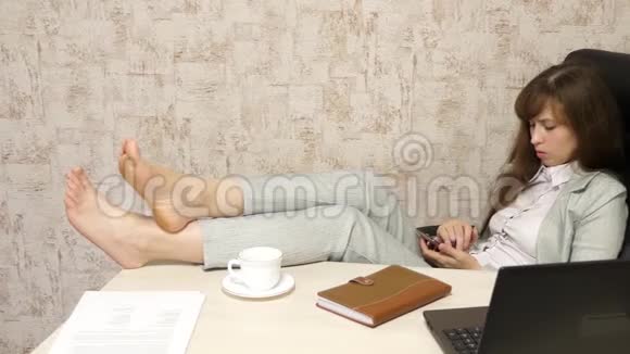 漂亮的女商人打电话光着脚坐在椅子上休息喝茶喝咖啡视频的预览图