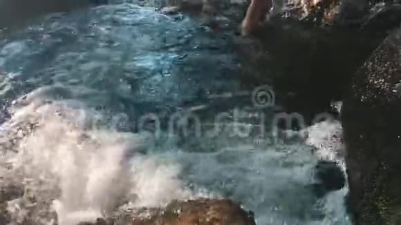 人在岩石和石头中间的河流的浅水中游泳视频的预览图